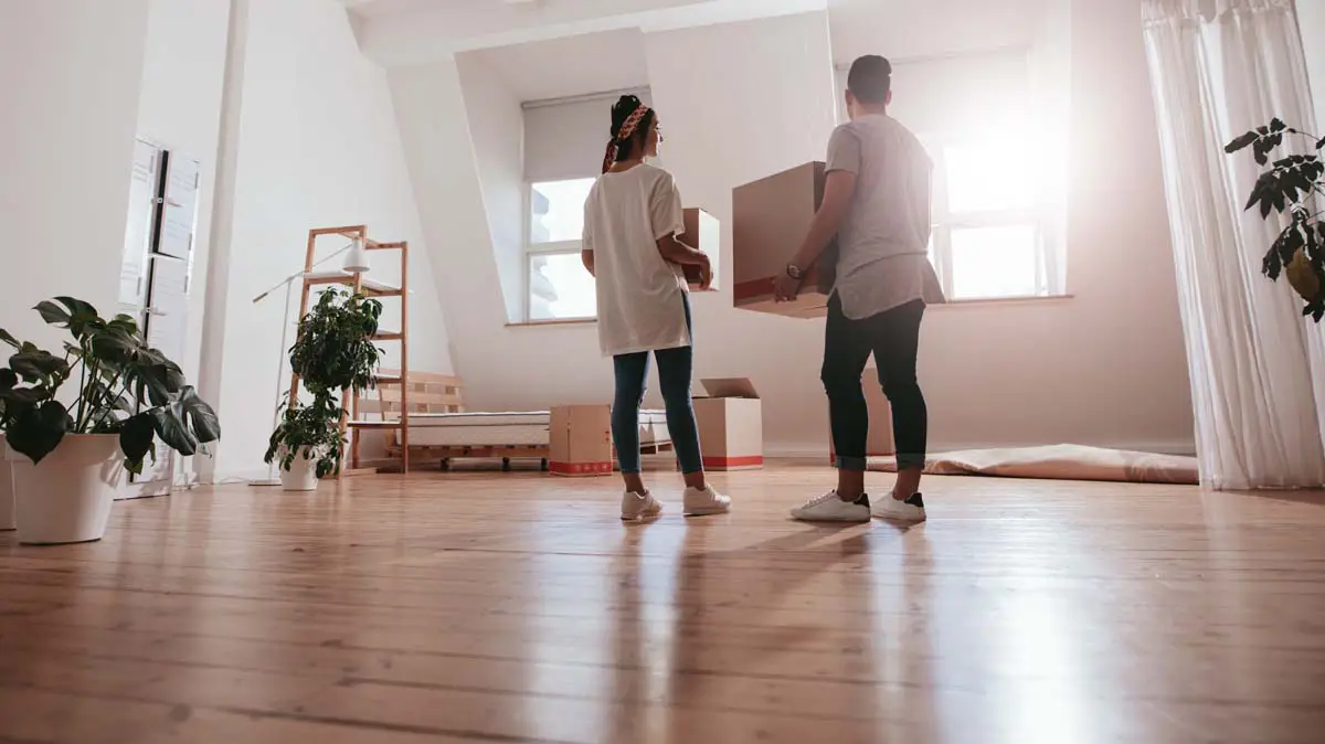 Couple carrying moving boxes into their new home