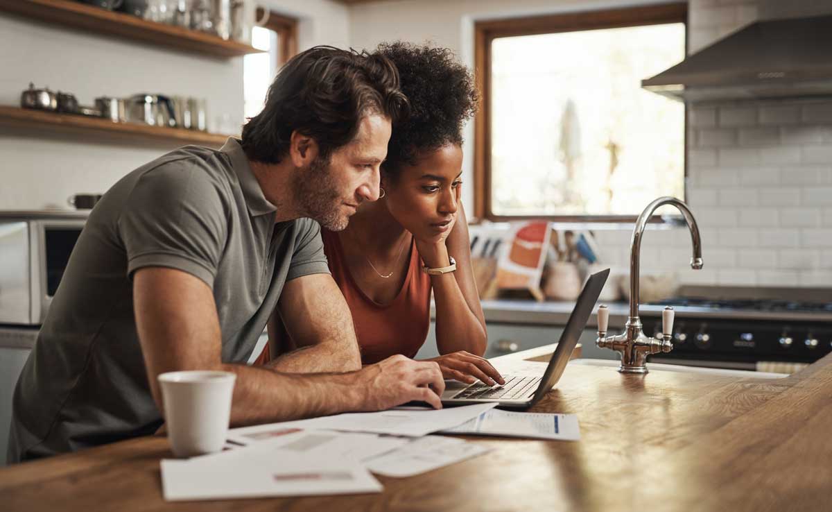 Couple reviewing mortgage documents on a laptop at home