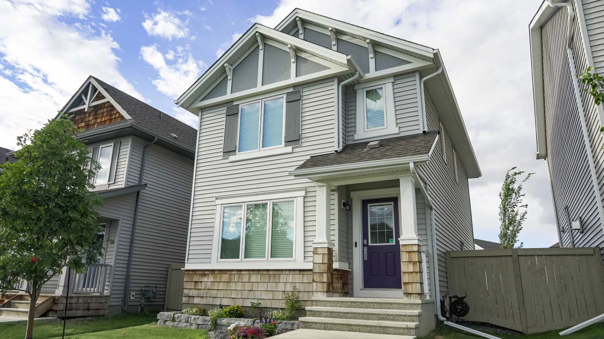 Home with grey shutters and mature landscaping